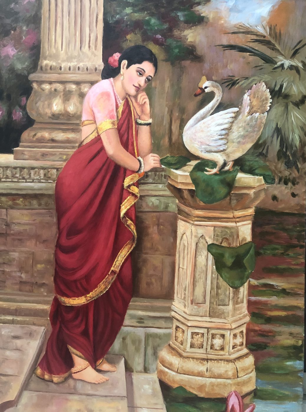 A woman in a red sari leaning toward a white swan by a lotus pond